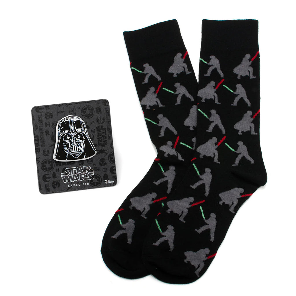 Black crew socks featuring a pattern of Darth Vader and Luke Skywalker dueling with lightsabers, next to a Darth Vader lapel pin.