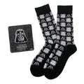A pair of black crew socks with a repeating pattern of Darth Vader and Stormtrooper helmets next to a Star Wars Darth Vader lapel pin.
