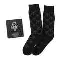 A pair of charcoal gray dress socks with a repeating Mythosaur skull pattern paired with a silver and black Mandalorian Mythosaur lapel pin.