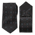 Close up of a black necktie with Mandalorian helmet and Mythosaur skull motifs in black with electric blue floral accents.