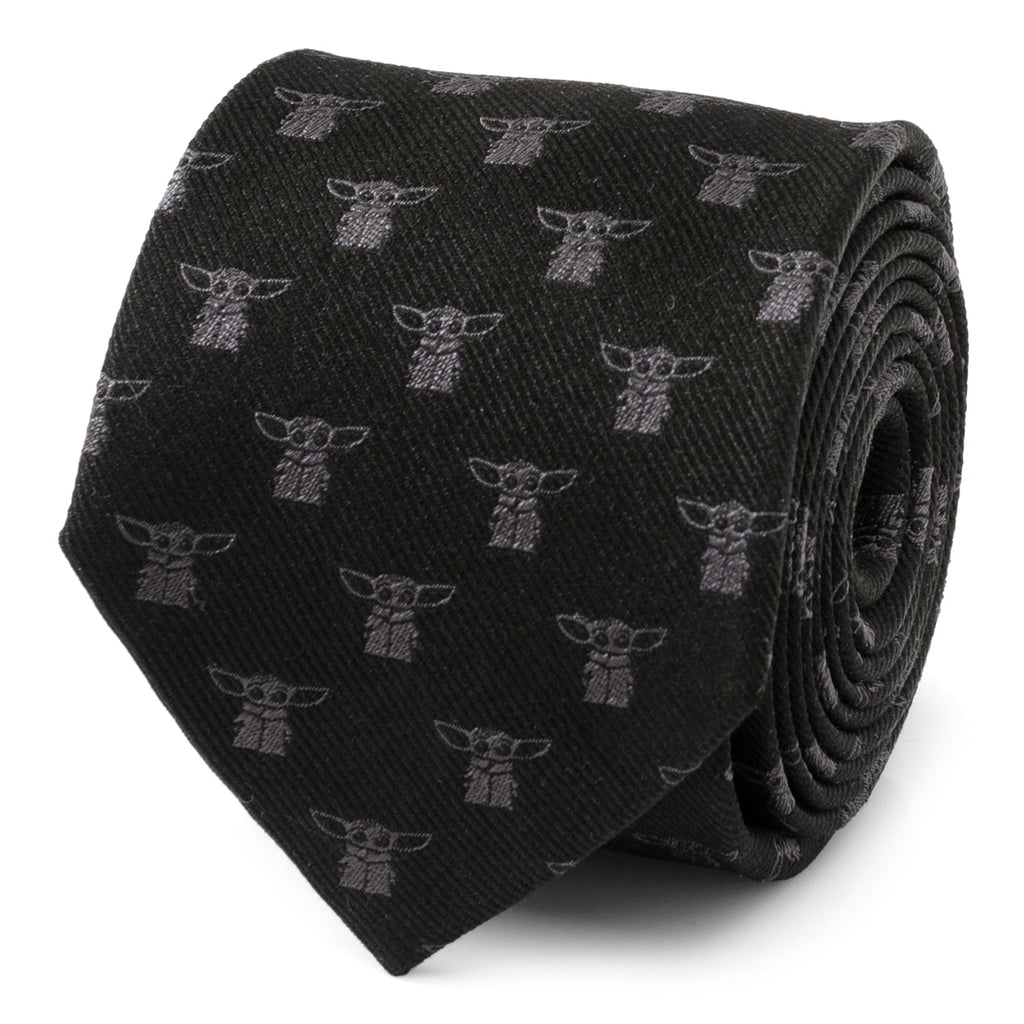A black silk necktie featuring a repeating print of Grogu (Baby Yoda) from The Mandalorian, shown both rolled up and styled on a mannequin.