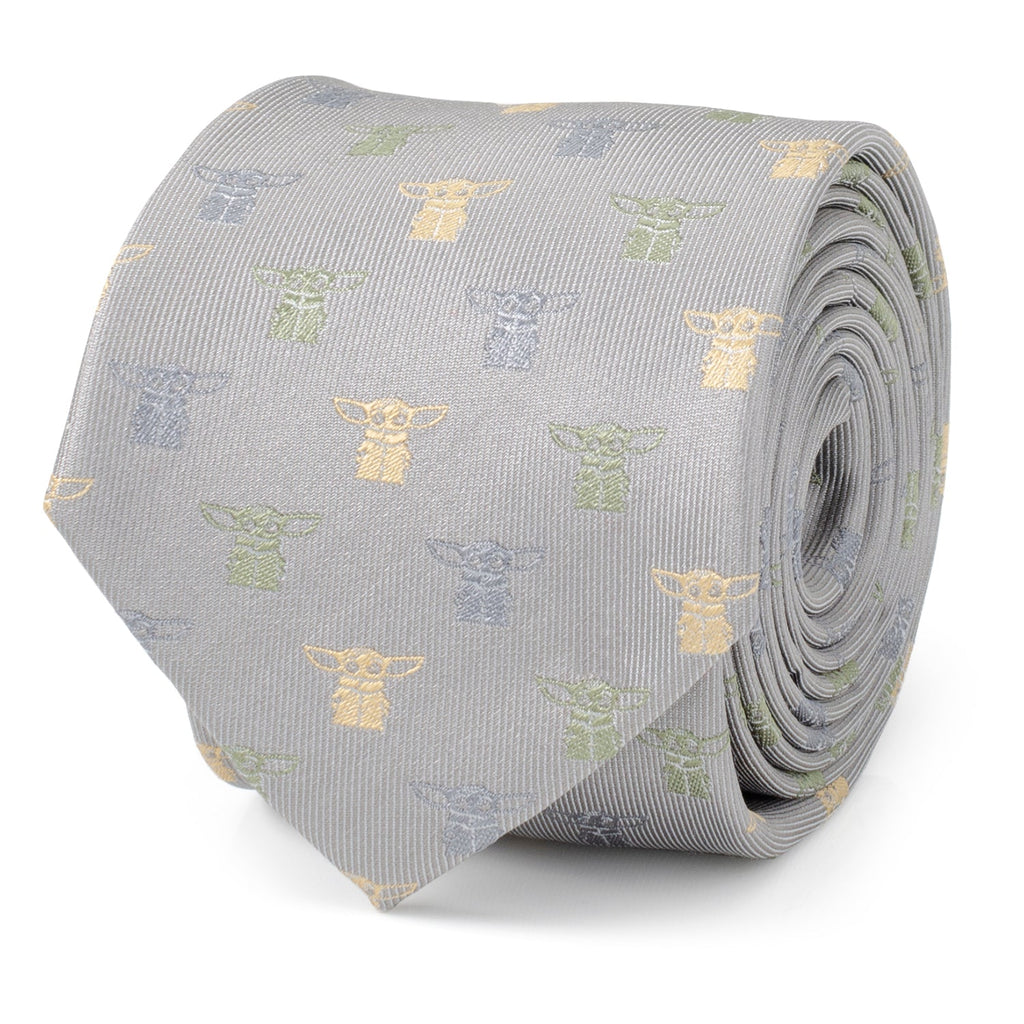 Close up of a cloud grey silk necktie featuring a small repeating pattern of Grogu from The Mandalorian in silver, sage green, and yellow stitching.