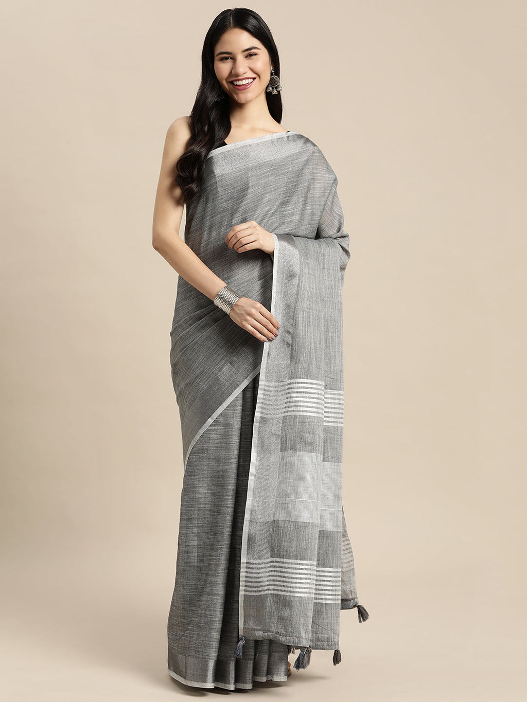 Dark grey woven linen saree with gold zari border and decorative tassels