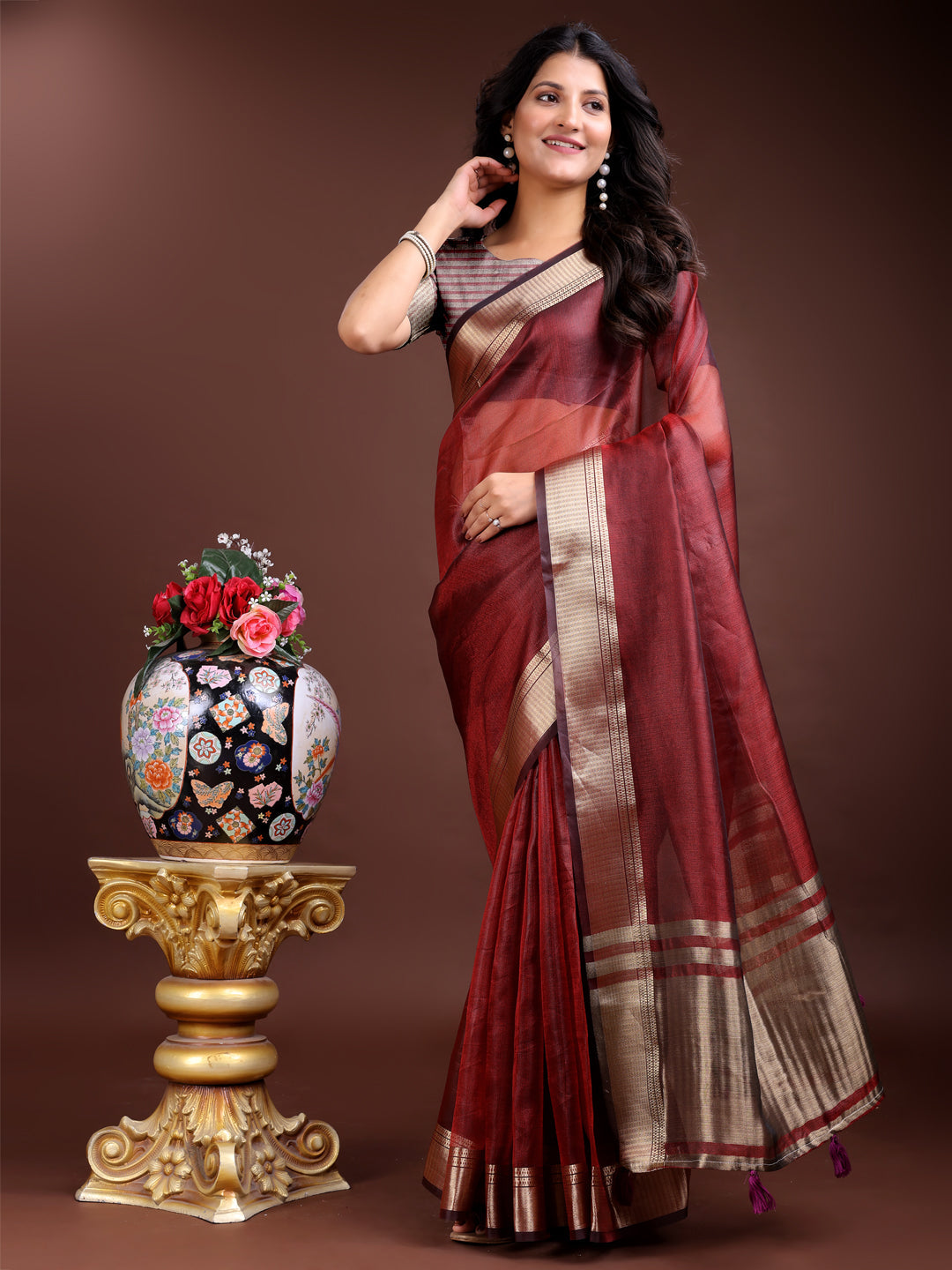 Red organza saree with intricate woven gold zari border and decorative tassels