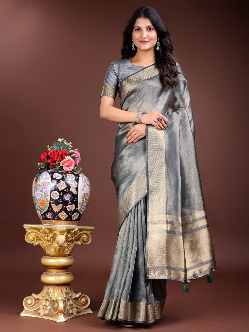 Silver-toned organza saree decorated with intricate zari patterns and tassels.