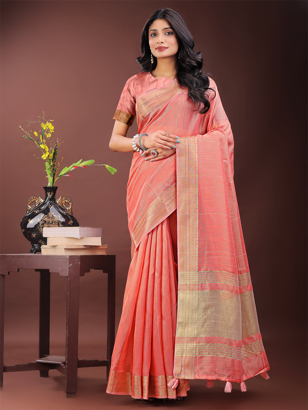 Elegant peach organza saree featuring a golden zari border and pallu