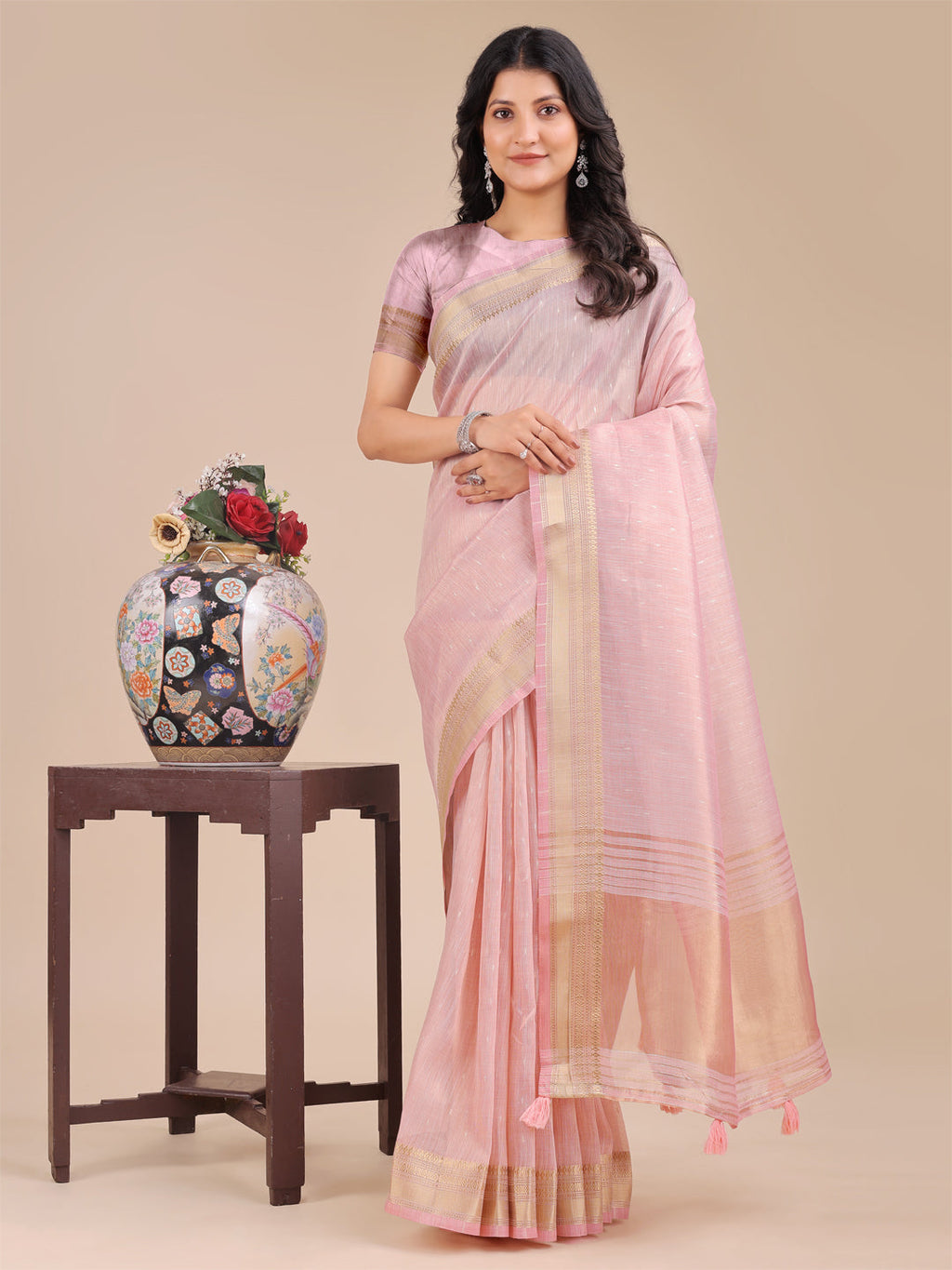 A beautiful Light Pink Organza saree with woven zari borders and decorative tassel pallu details.