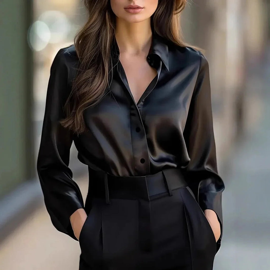A woman wearing a sleek, long-sleeved black satin button-down blouse with a classic lapel collar.