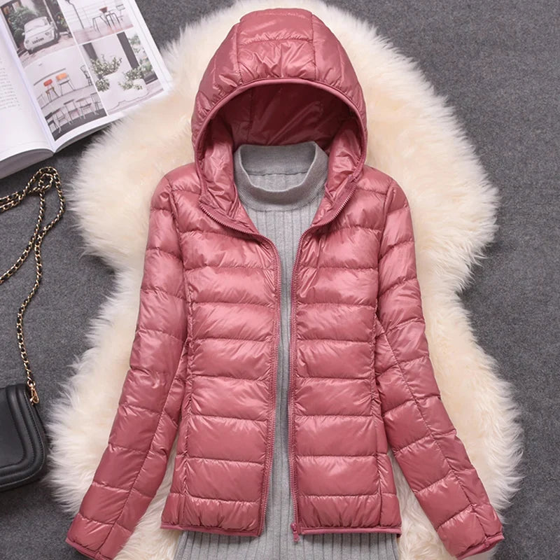 Pink puffer jacket on a fur surface with an open magazine and black bag in the background.