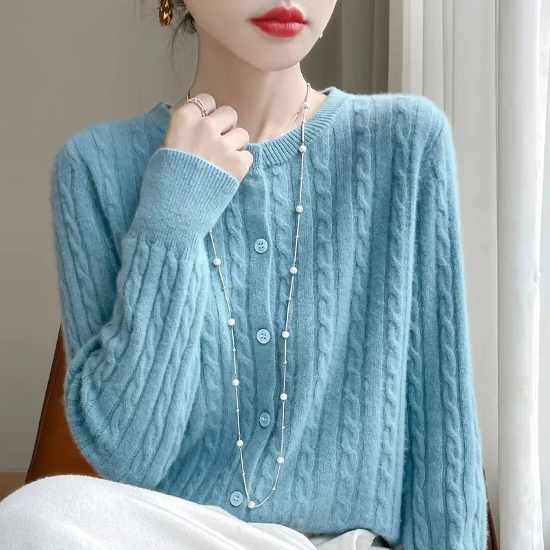 A woman wearing a soft cable knit button-down cardigan available in blue and red
