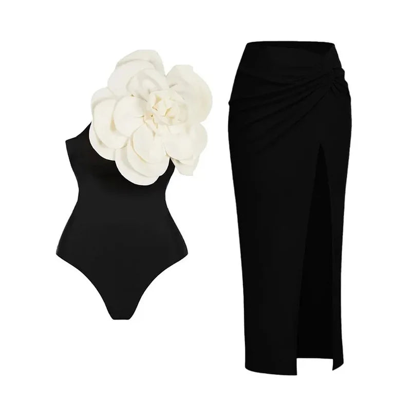 A black one-piece swimsuit featuring a large white rose applique, shown next to a matching black side-slit skirt.