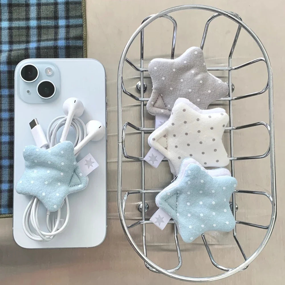 A collection of handmade star-shaped fabric cord organizers with white polka dots in light blue, white, and grey, neatly winding wired earphones.