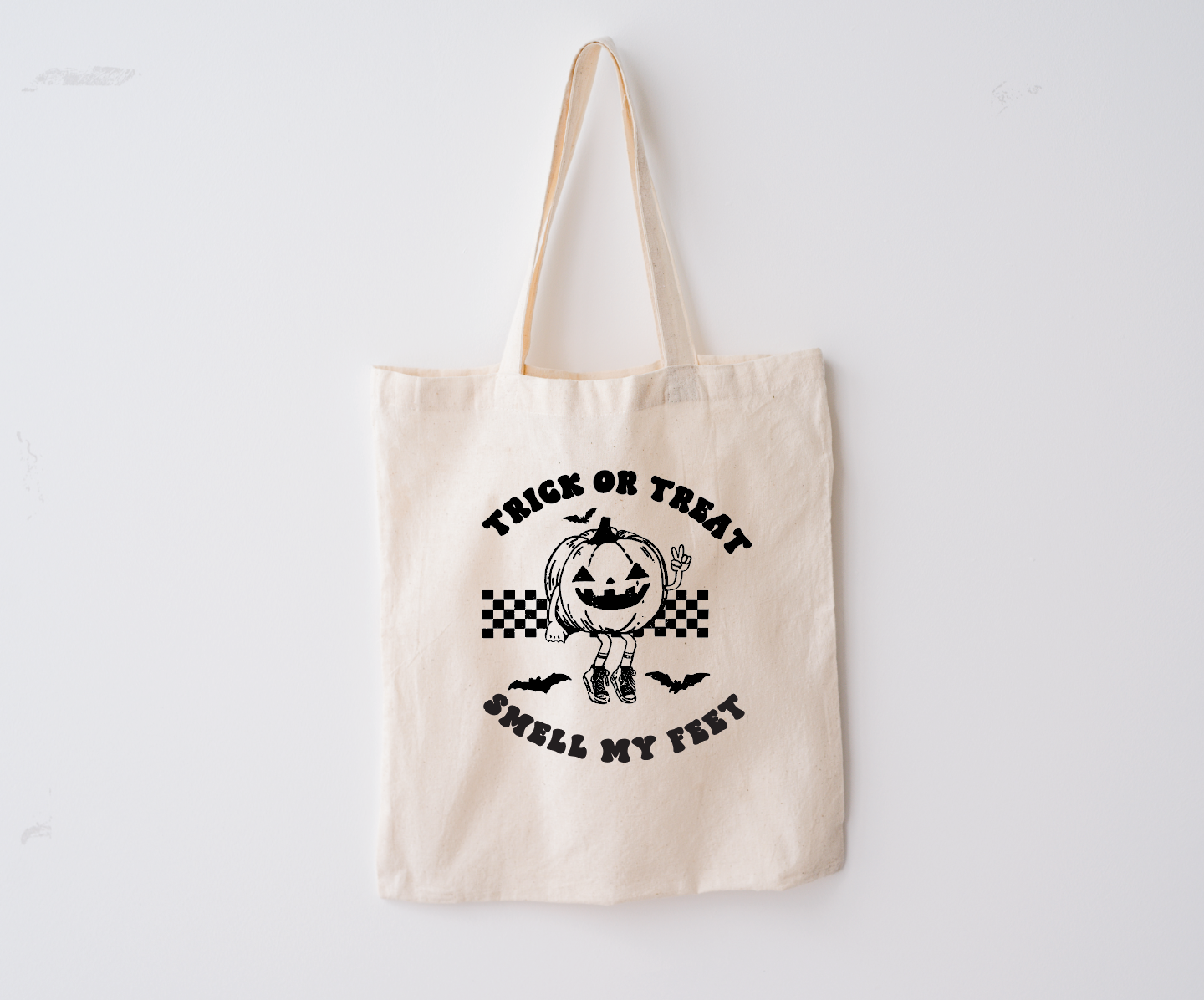Child holding a beige cotton Trick or Treat Smell My Feet Halloween candy bag