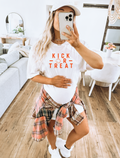 Pregnant woman wearing a white short-sleeve maternity tee with orange 'Kick or Treat' graphic text.