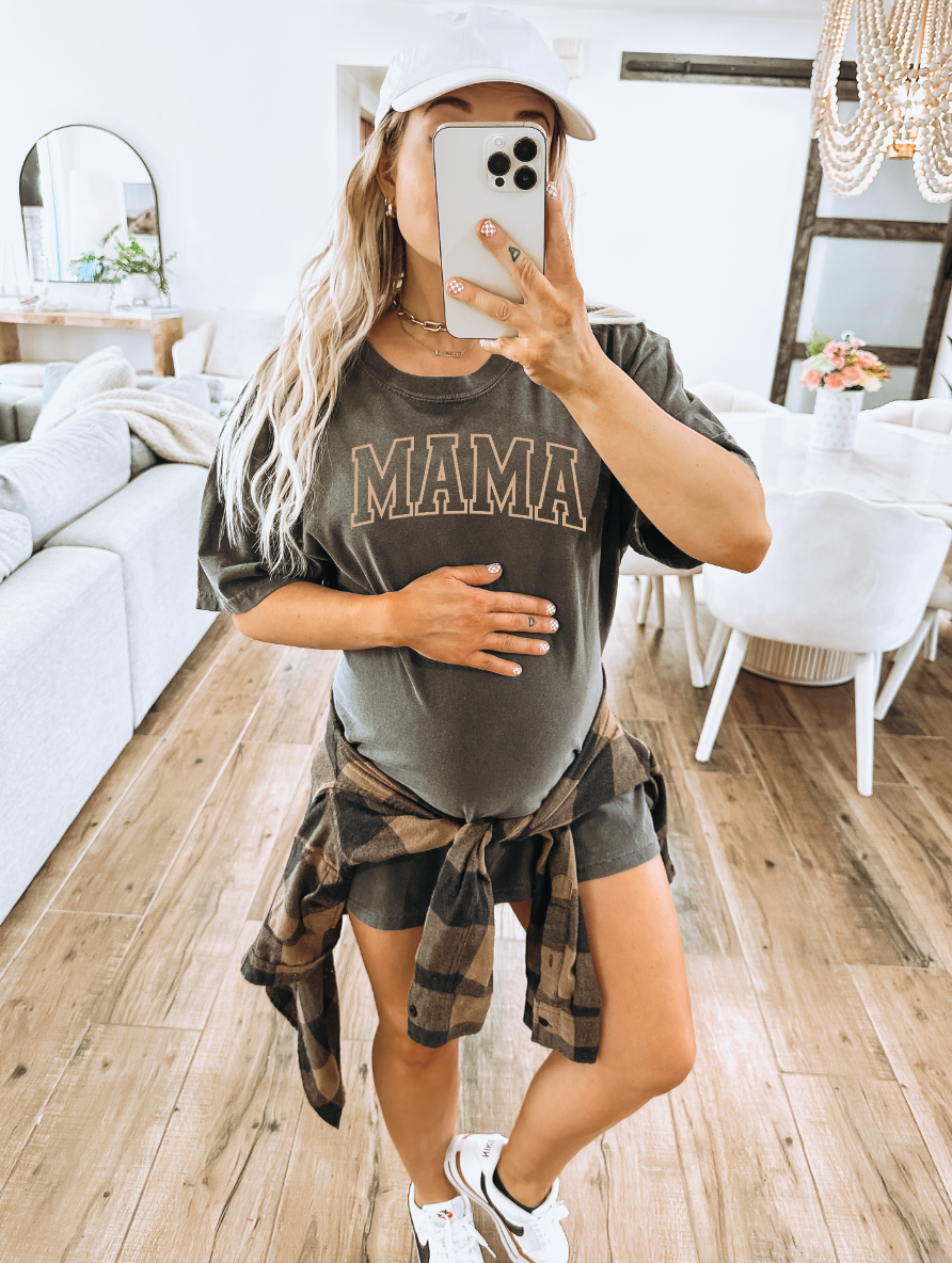 Woman wearing a relaxed-fit Mama Varsity crew neck t-shirt in charcoal grey or tan.
