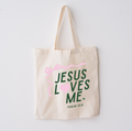 Natural beige cotton market tote with forest green text reading Jesus Loves Me and light pink graphic accents