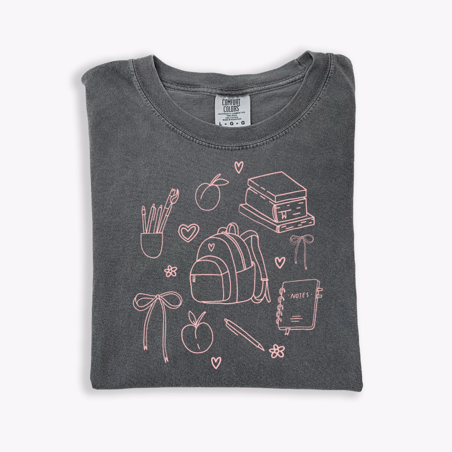 A collection of Back to School Doodles graphic t-shirts in various colors including pink and black.