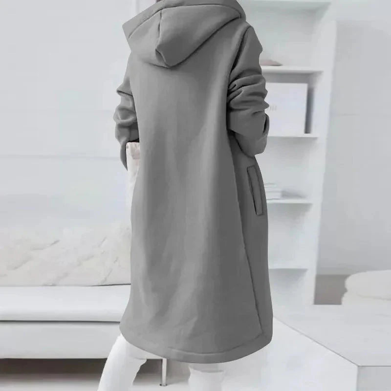 Gray hooded coat worn by a person in a minimal white room.