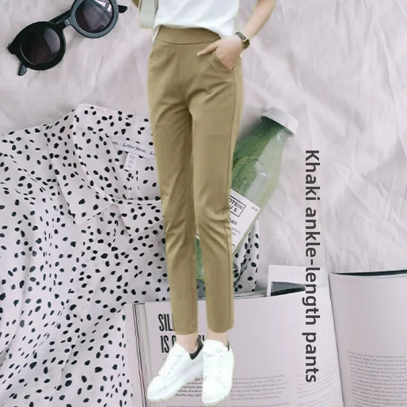 Model wearing high-waisted beige and black ankle-length straight-leg trousers with white sneakers