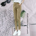 Model wearing high-waisted beige and black ankle-length straight-leg trousers with white sneakers