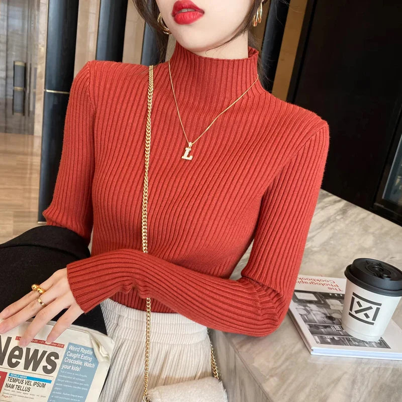 A woman wearing a fitted mock neck ribbed knit sweater in terracotta orange, showing the texture and slim fit.