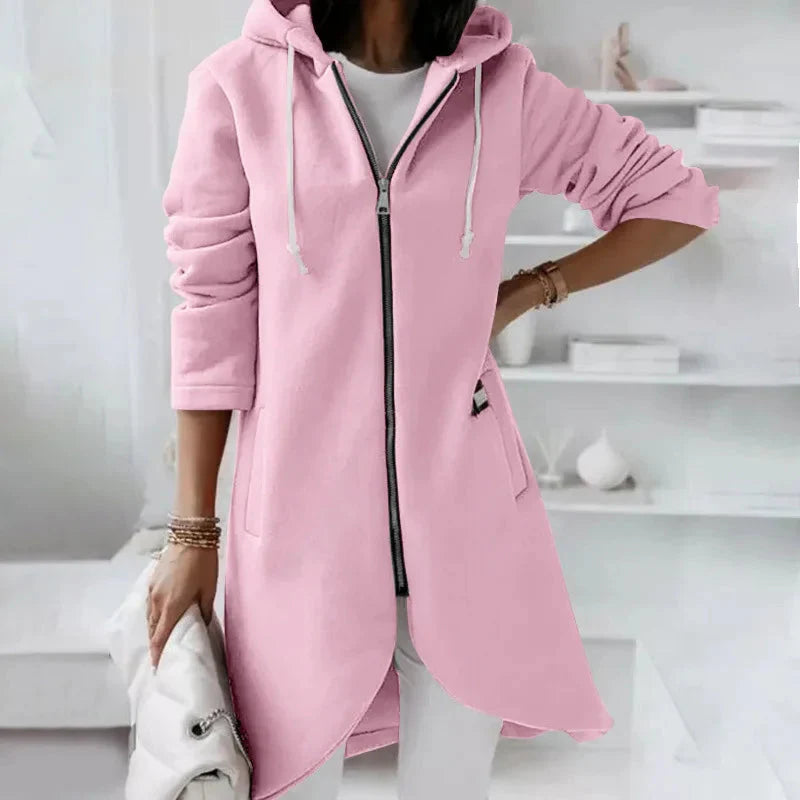 Person wearing a pink hoodie with a zipper in a minimalistic room.