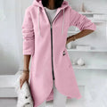 Person wearing a pink hoodie with a zipper in a minimalistic room.