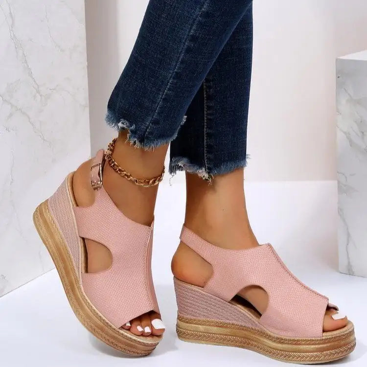 A pair of light pink peep-toe wedge sandals with a platform sole and gold buckle closure