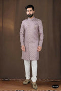 A toddler wearing a pink woven jacquard kurta with white pyjamas for a festive occasion