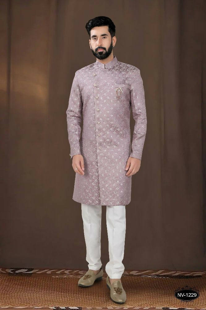 A toddler wearing a pink woven jacquard kurta with white pyjamas for a festive occasion