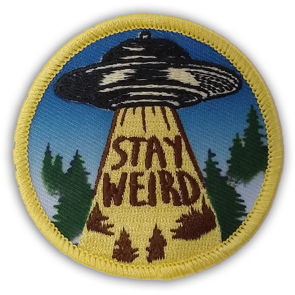 Circular Stay Weird patch featuring a retro UFO flying saucer and a bright yellow tractor beam