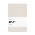 Close up of a Bone colored hardcover stone paper notebook with an elastic band and ribbon bookmark.