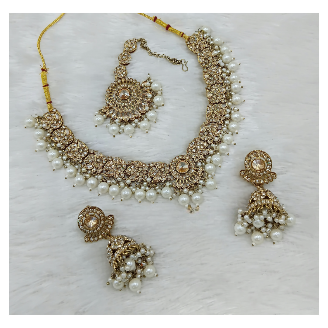 Exquisite cream-colored stone work necklace set including matching earrings and tikka for formal occasions