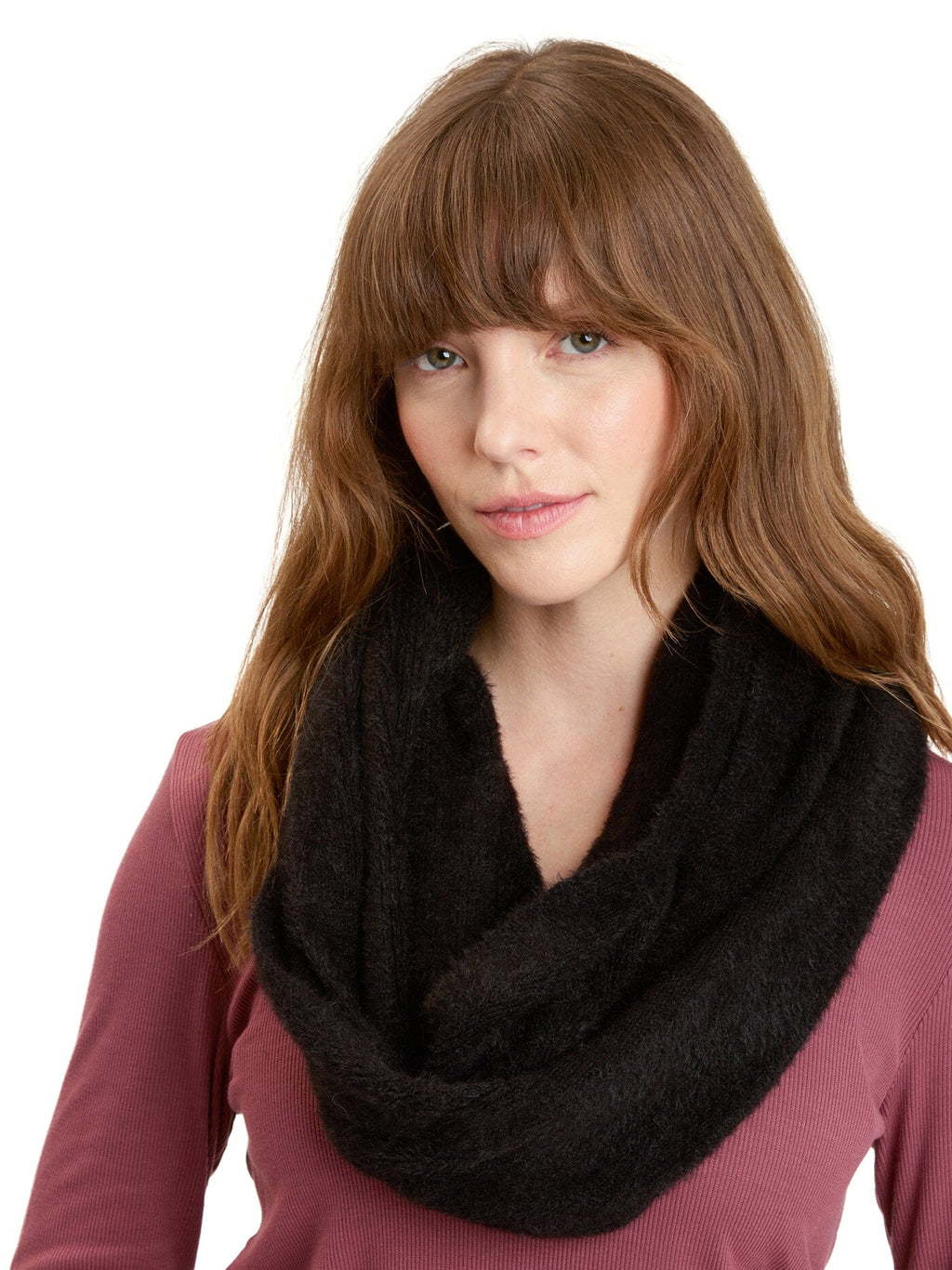 Woman wearing a soft black fuzzy knit infinity scarf with a minimalist winter outfit.
