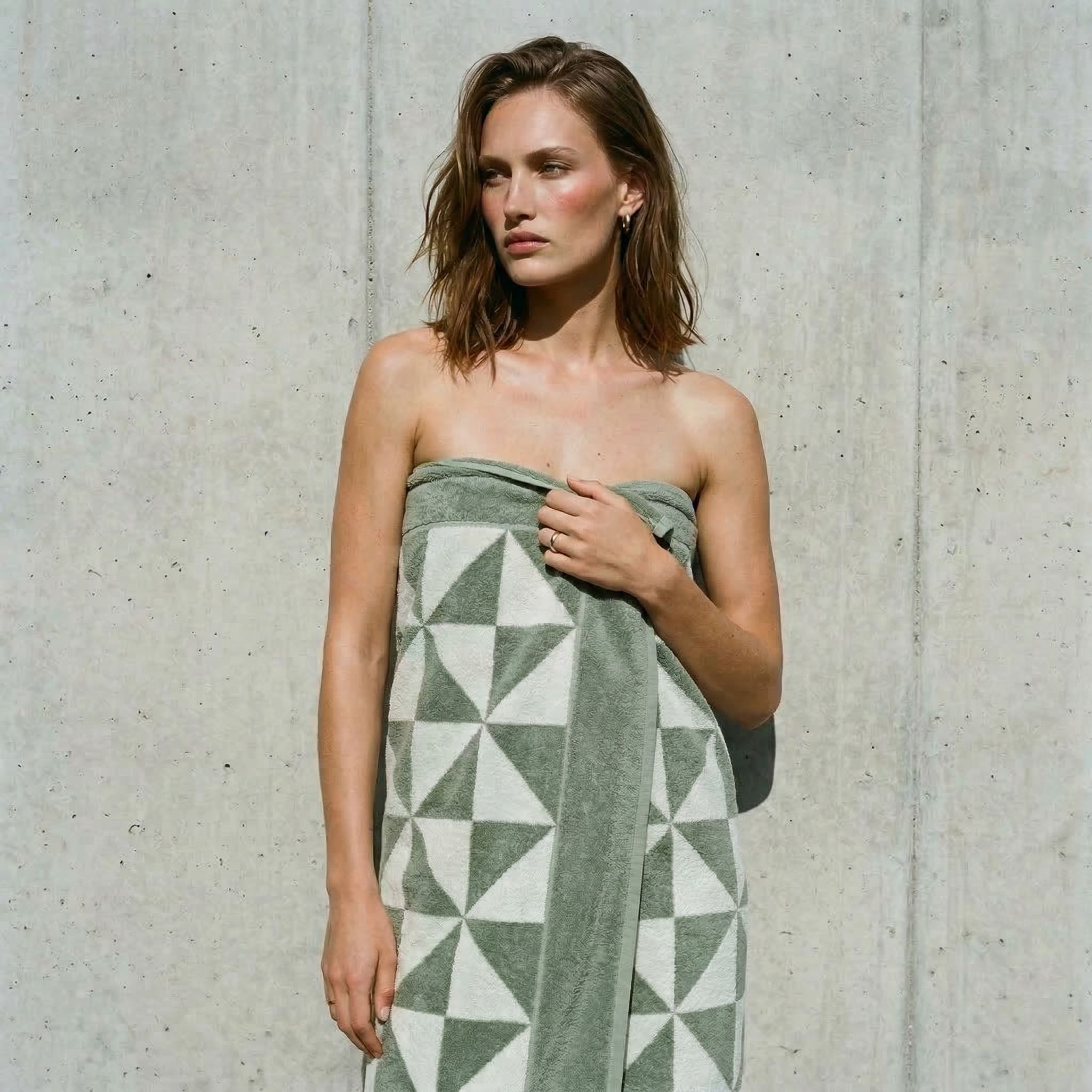 A person wrapped in a sage green and white geometric pattern Australian cotton bath towel.