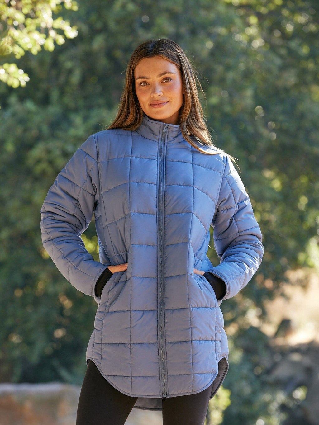 Woman wearing a muted dusty blue long packable puffer jacket in a relaxed fit.