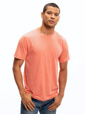 Men wearing a solid coral heathered tone crew neck triblend jersey tee in a minimalist casual setting.