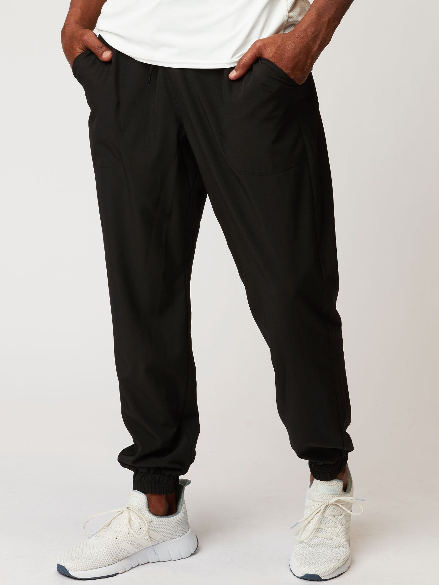 Men wearing black Francis Woven ReActive Joggers with a tapered fit in a sporty gym setting.