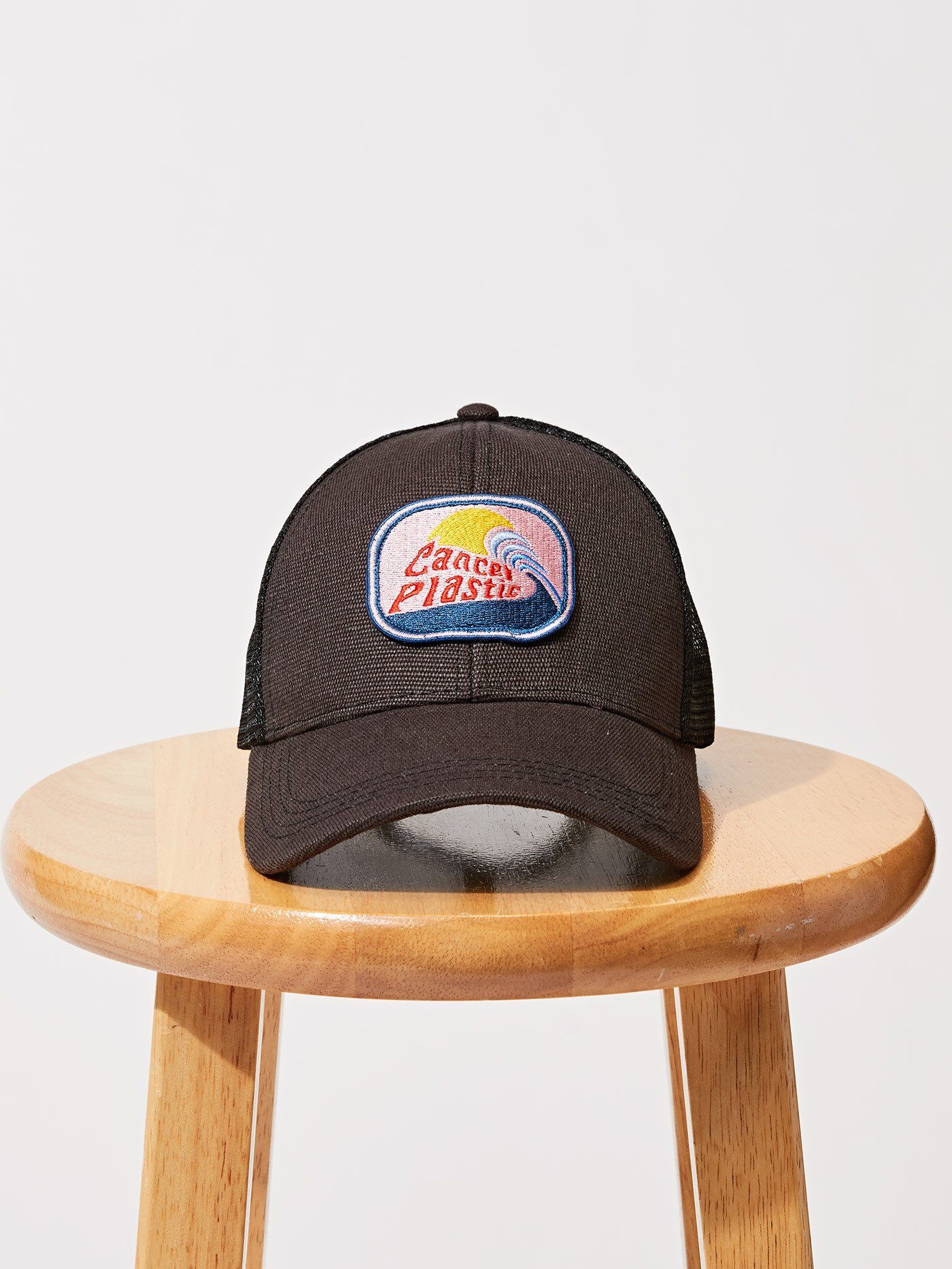 Black Cancel Plastic trucker hat with recycled mesh back and embroidered surf-culture logo.