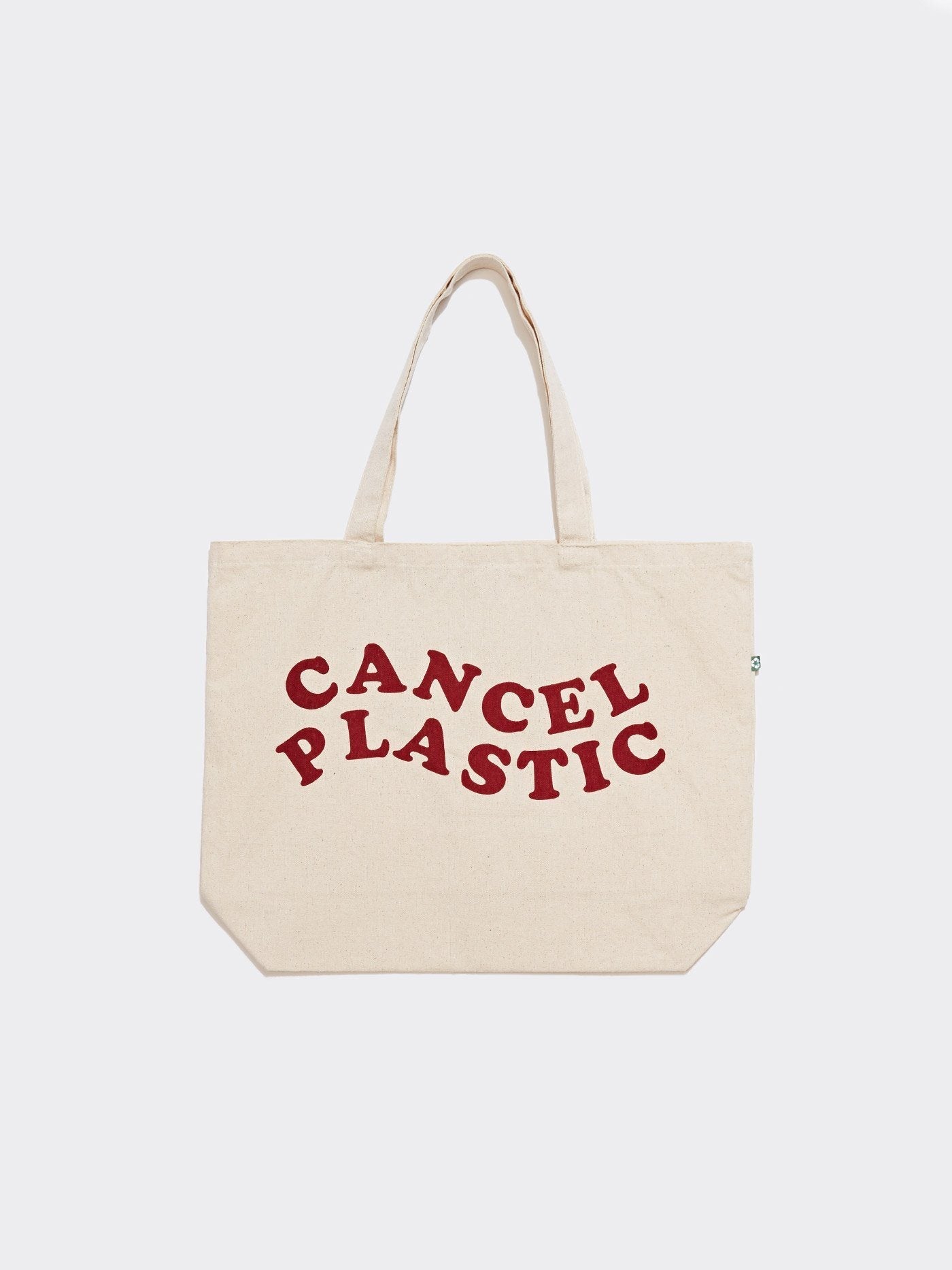 Natural beige canvas tote bag with deep red Cancel Plastic graphic text, 20x14 inches