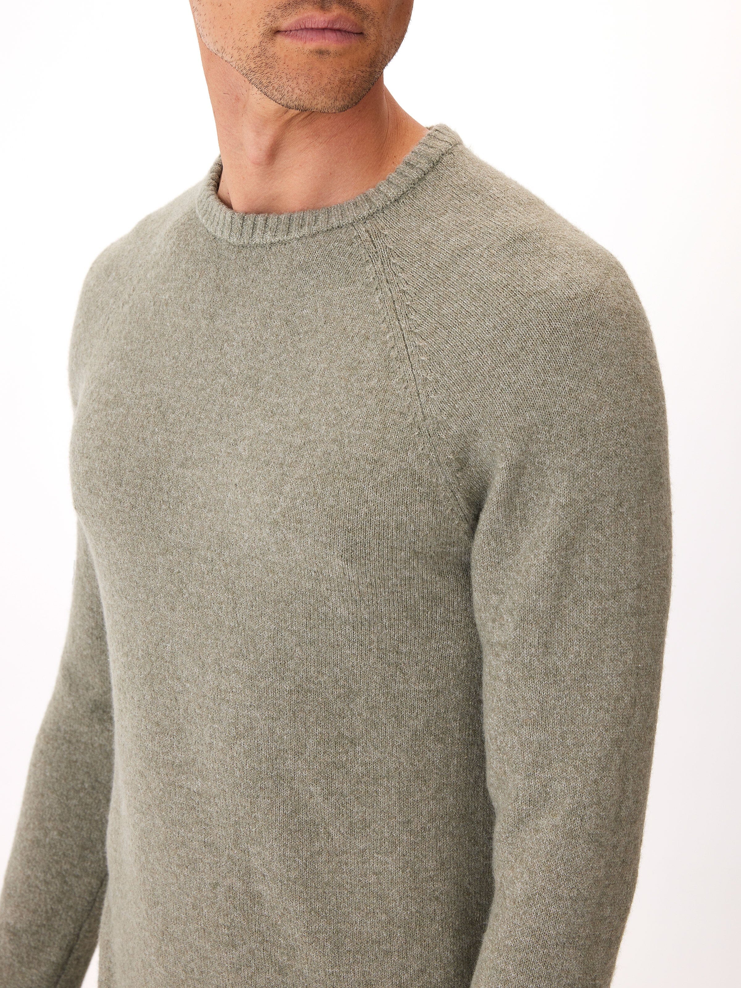 Men wearing an olive green raglan crew neck sweater in a minimalist knit fabric