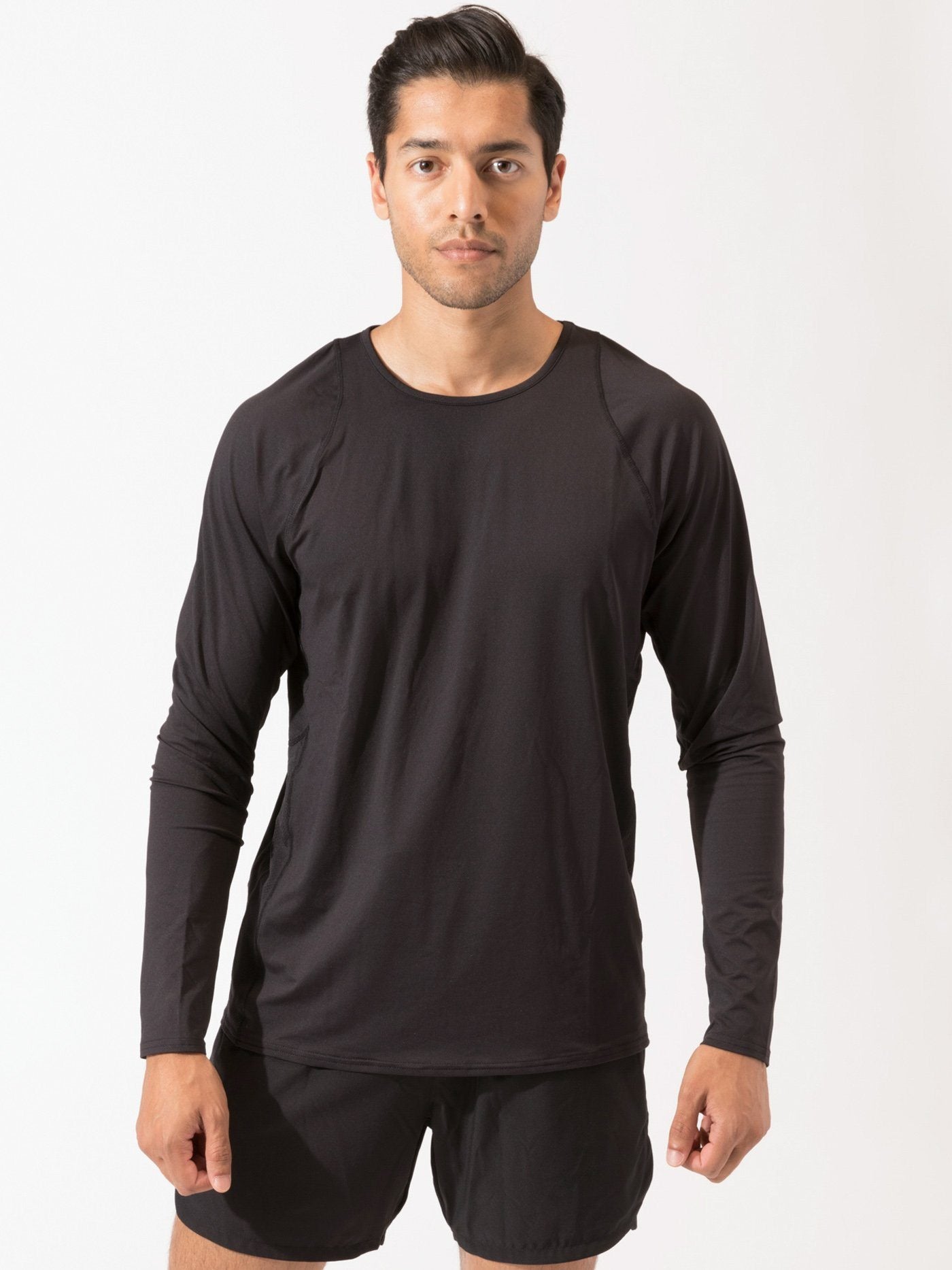 A man wearing a solid black fitted long sleeve crew neck activewear tee.