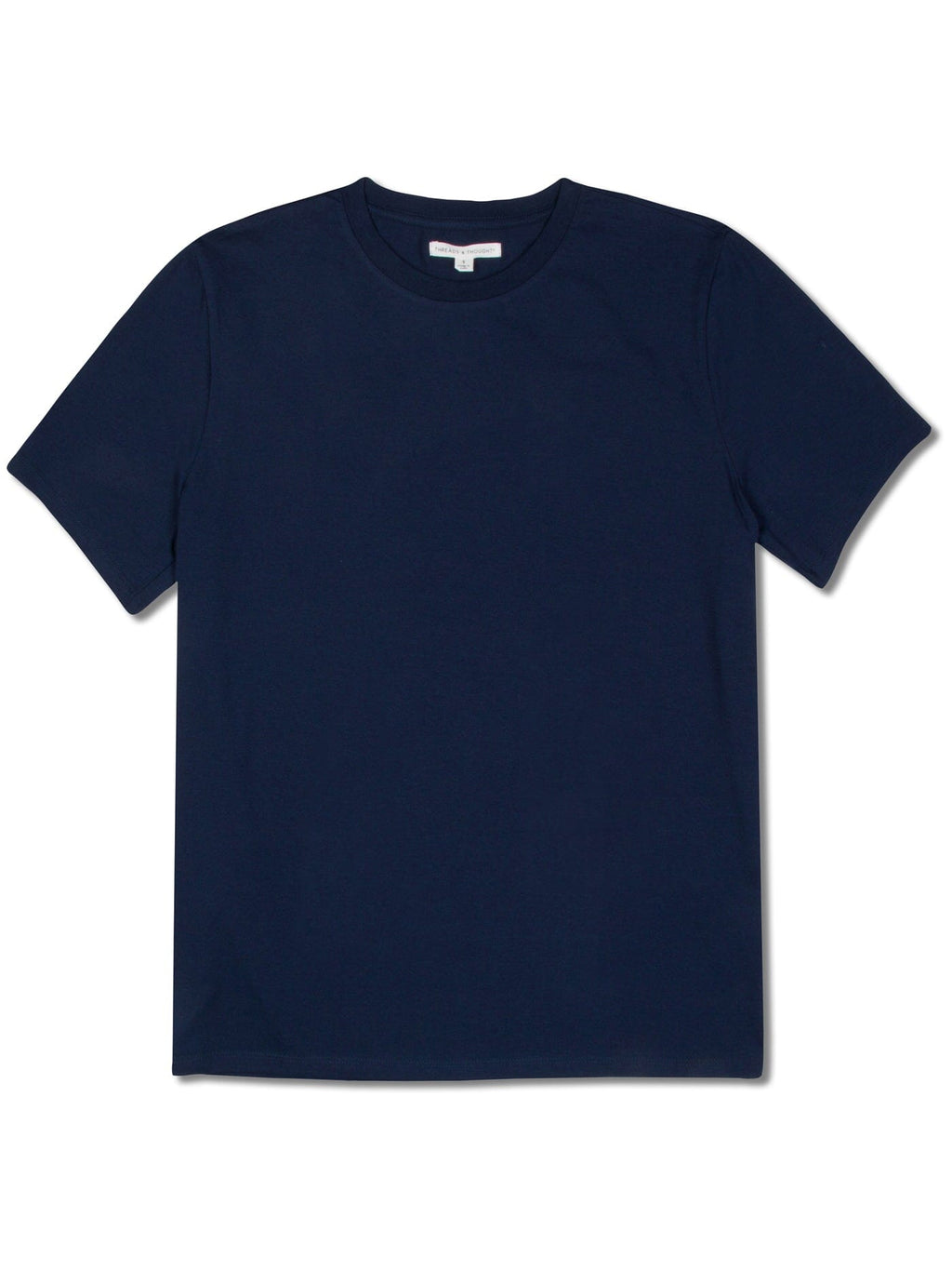 A man wearing a solid navy short sleeve crew neck t-shirt in a minimalist, casual lifestyle setting.