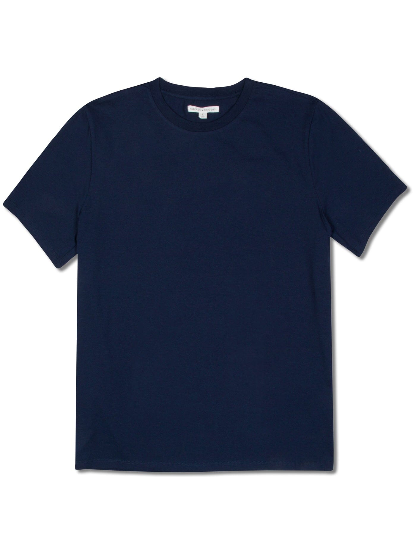 A man wearing a solid navy short sleeve crew neck t-shirt in a minimalist, casual lifestyle setting.