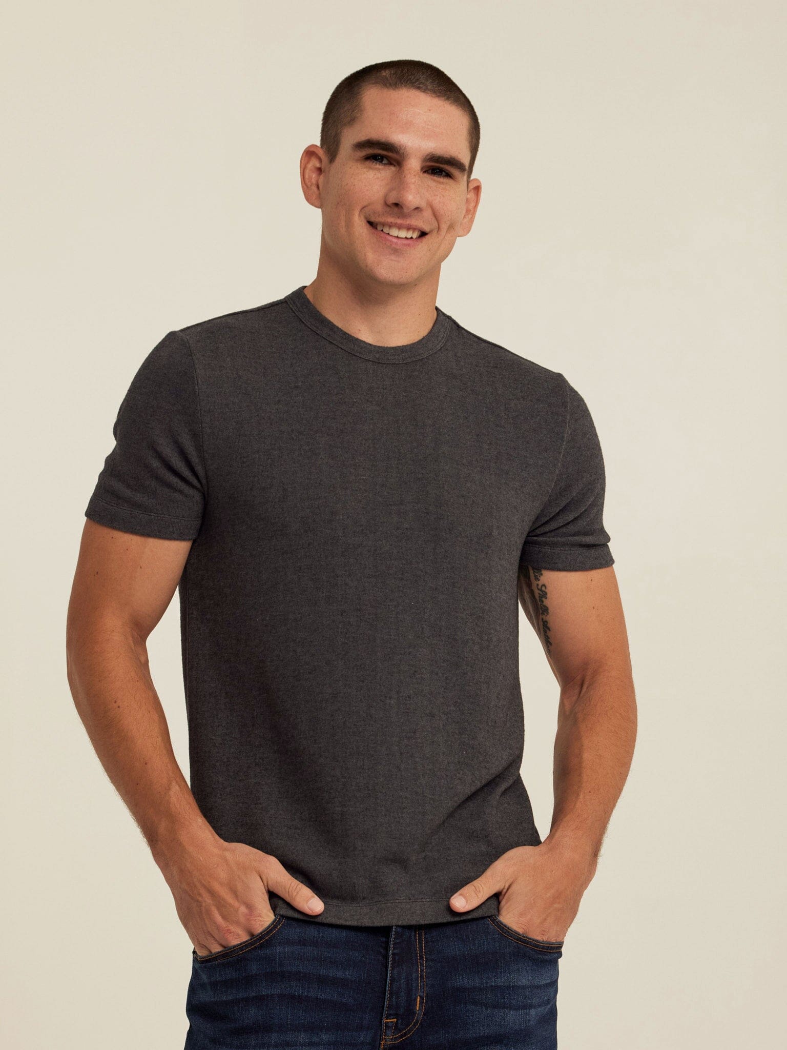 Man wearing a charcoal grey Gil sweater knit short sleeve tee with a clean tailored fit.