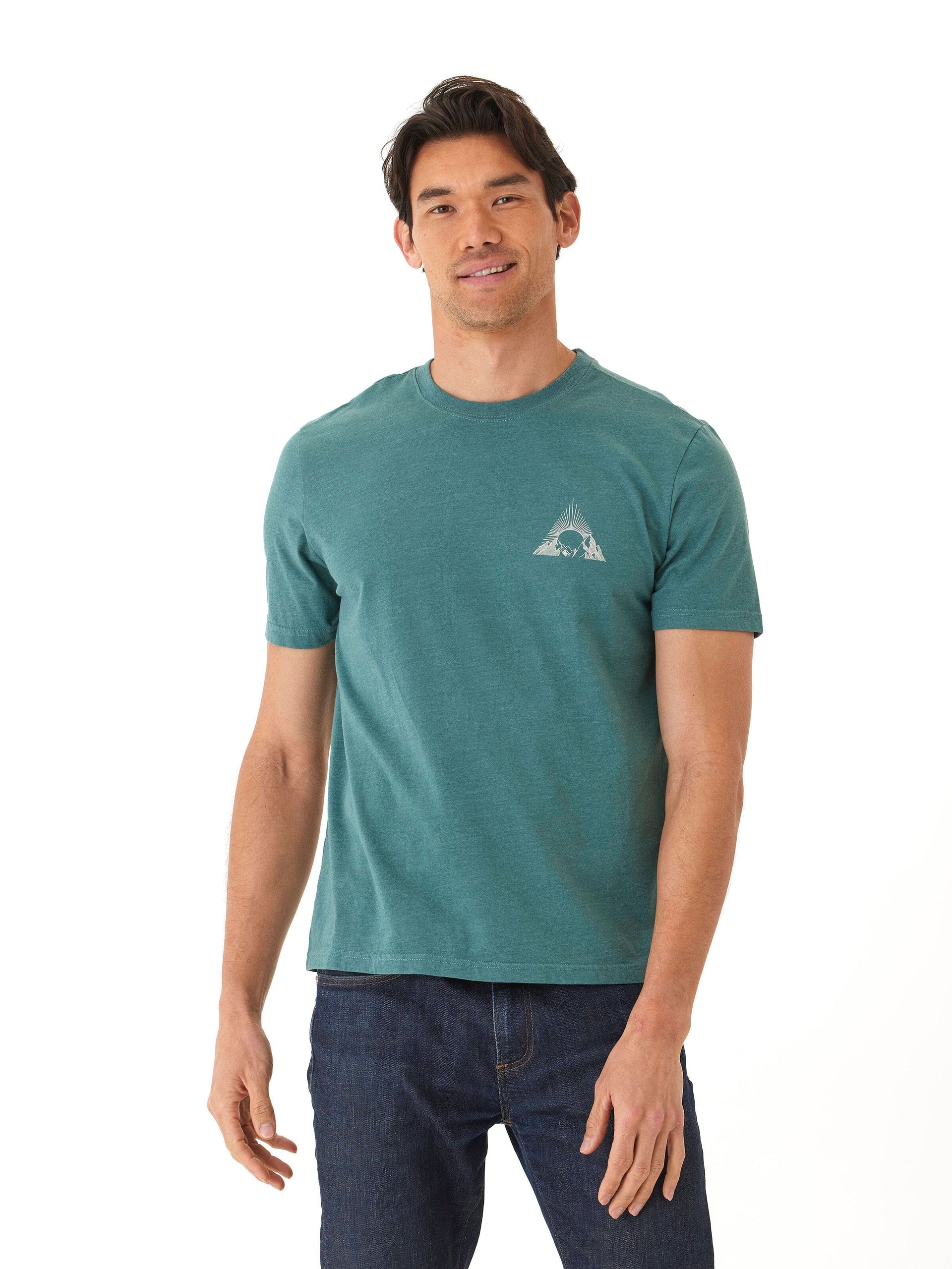 A man wearing a soft wash teal graphic tee in a minimalist outdoor setting.
