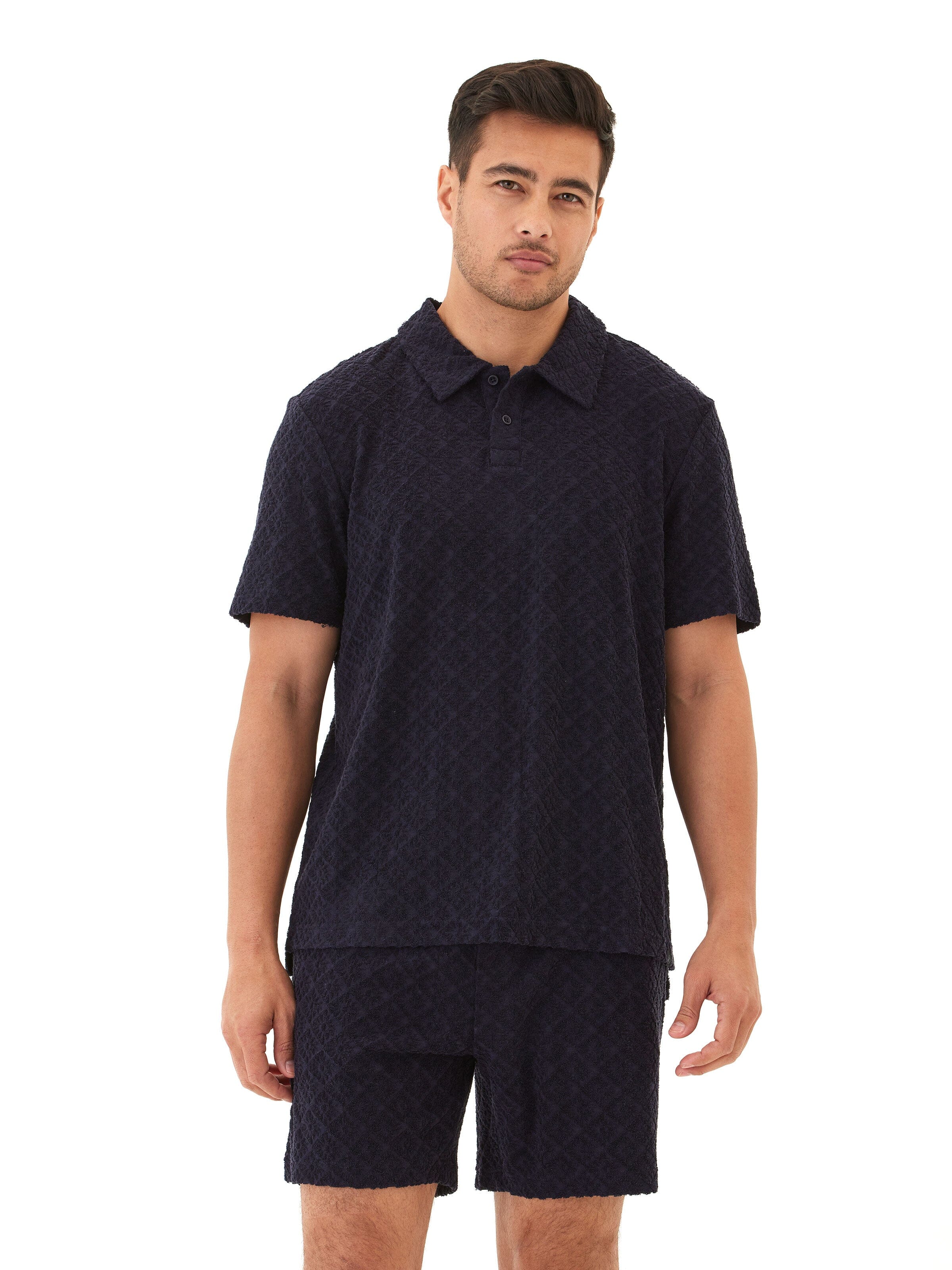 Men's navy polo shirt in textured jacquard terry fabric with a two-button placket and geometric pattern.