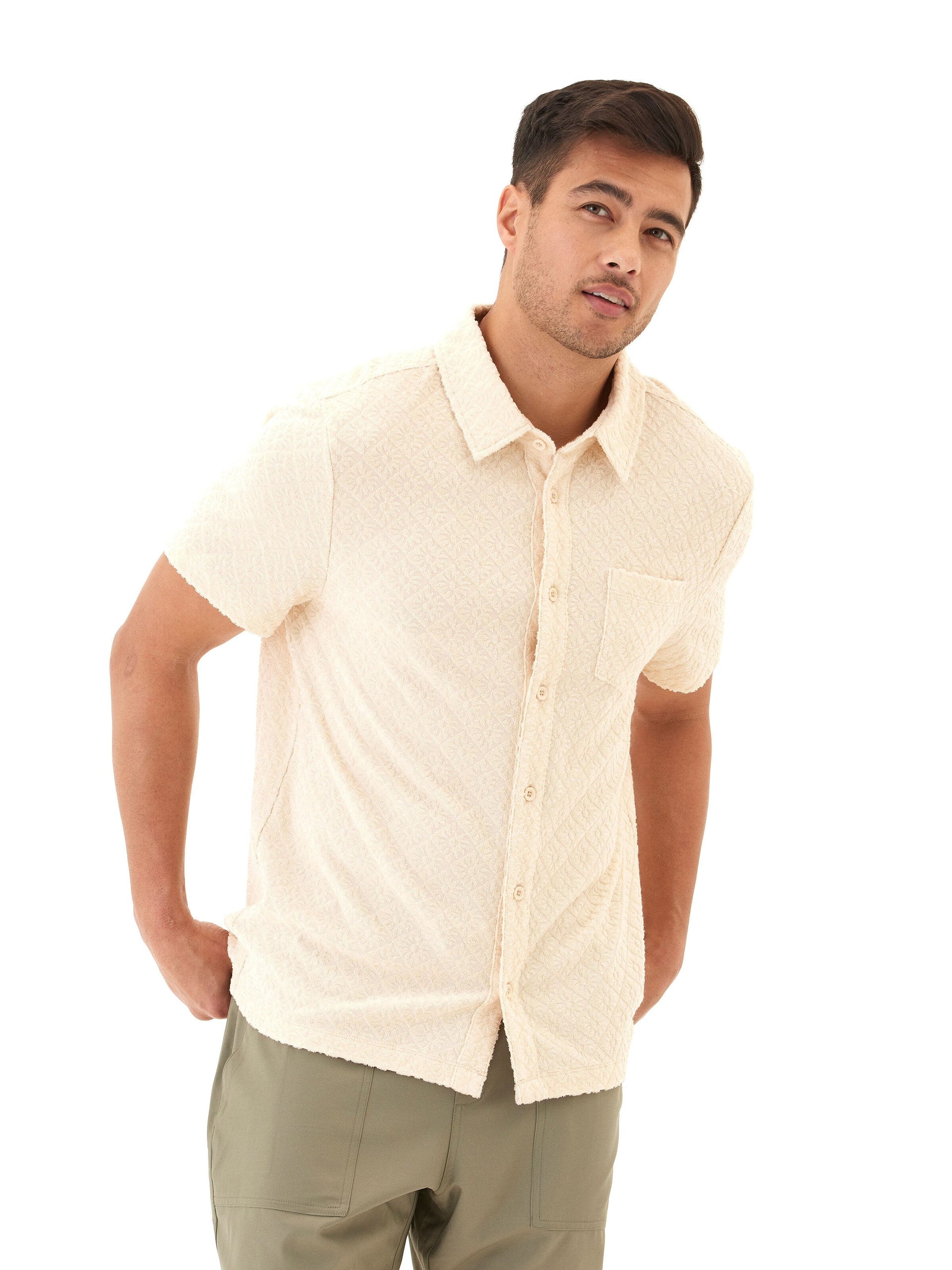 A man wearing a geometric jacquard terry short-sleeve button-down shirt in cream and beige tones.