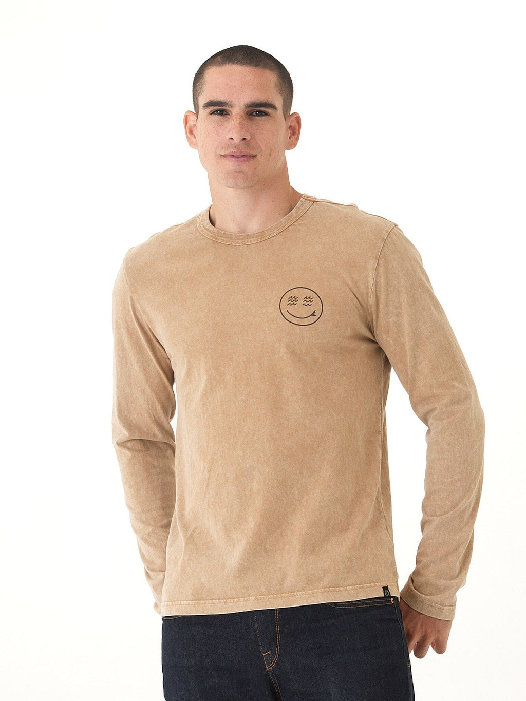Man wearing a mineral wash tan and brown graphic long sleeve tee with volcan-style side tab branding