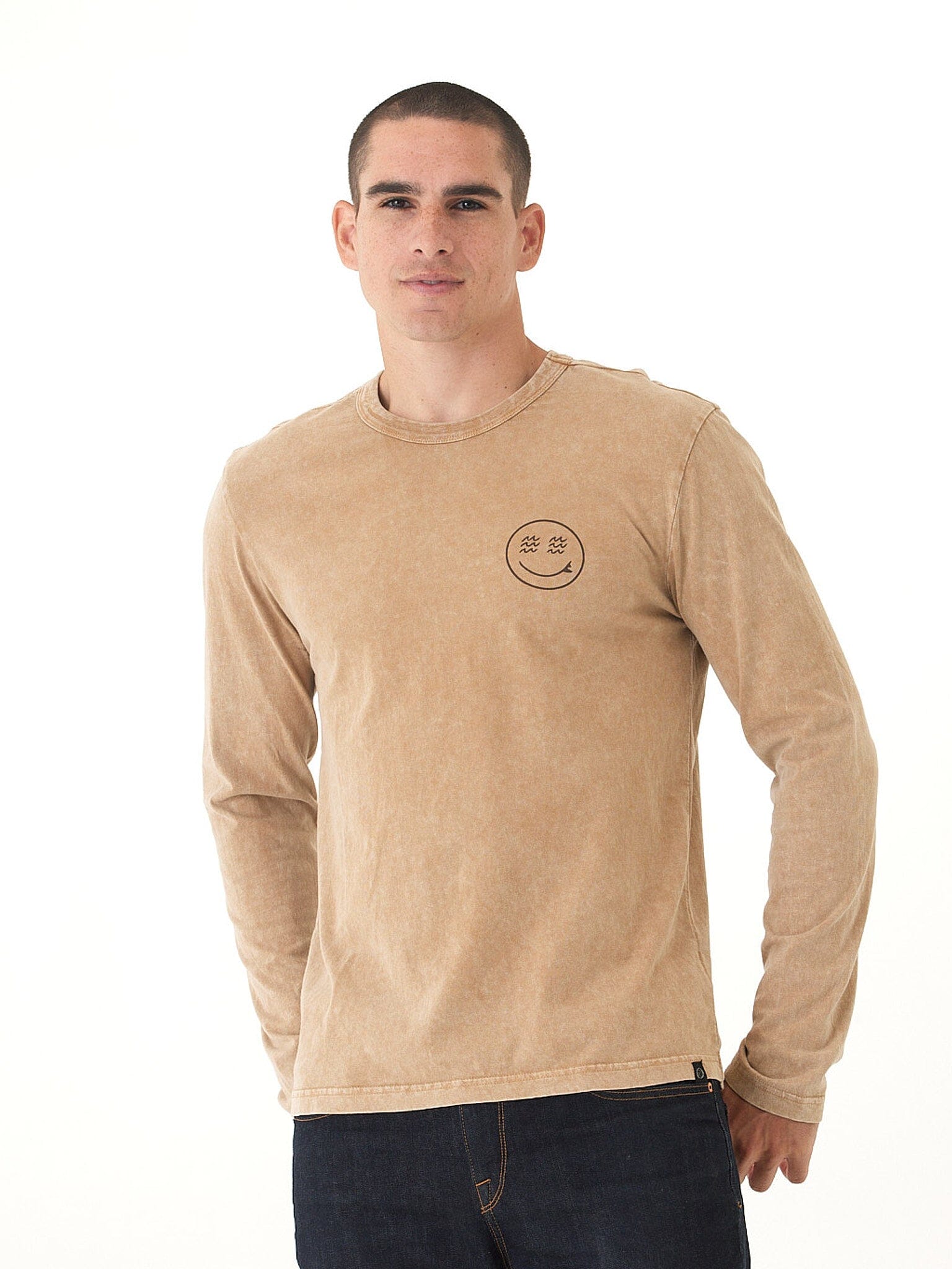 Man wearing a mineral wash tan and brown graphic long sleeve tee with volcan-style side tab branding